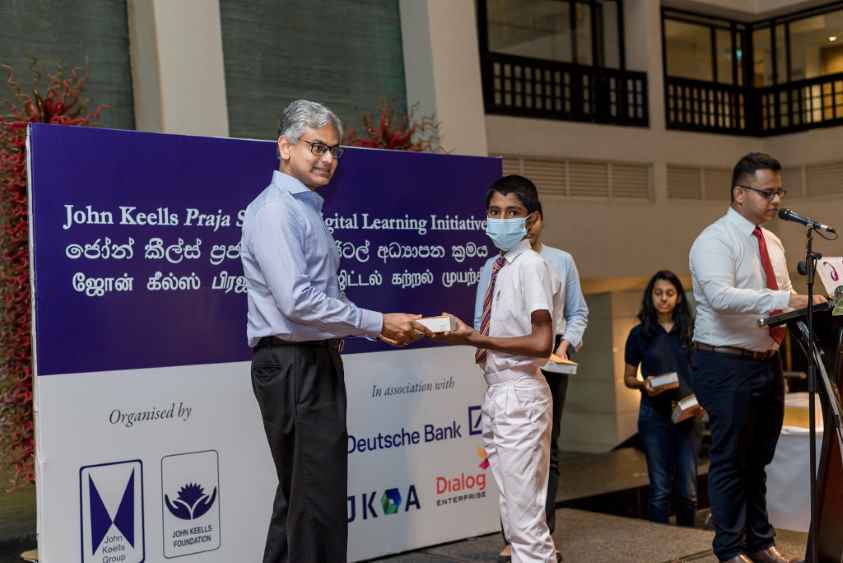 1.-JKH-Chairperson-Krishan-Balendra-handing-over-a-Digital-Tab-to-a-student-LBN.jpg